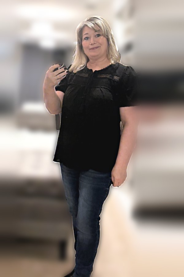 Mirror selfie of a woman wearing a black eyelet top with dark jeggings