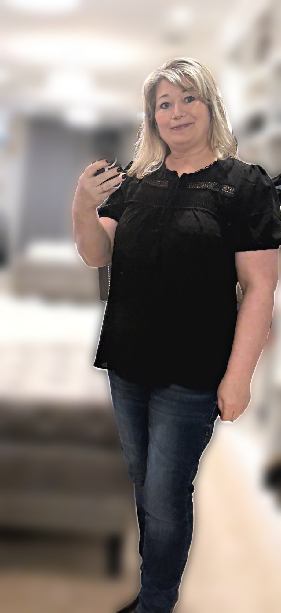 Mirror selfie of a woman wearing a black eyelet top with dark jeggings