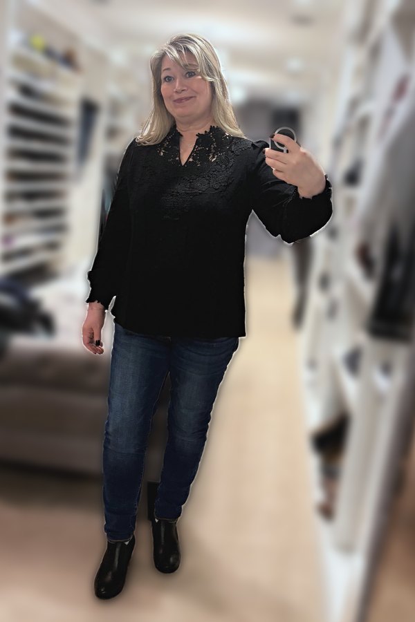 Mirror selfie of a woman wearing a black crochet-lace V-neck top, dark jeggings and black ankle boots