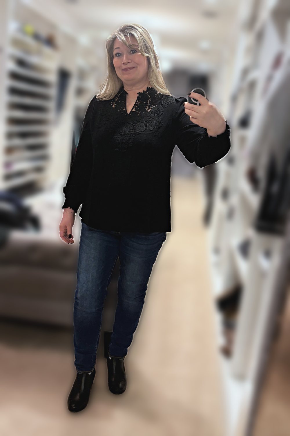 Mirror selfie of a woman wearing a black crochet-lace V-neck top, dark jeggings and black ankle boots