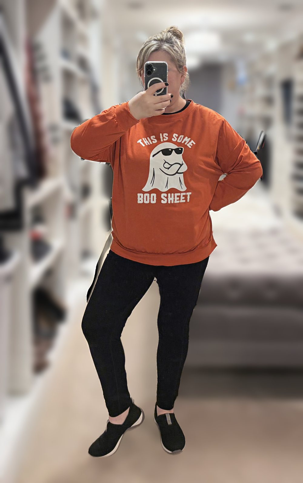 Mirror selfie of me, head to toe, in an orange “This Is Some Boo Sheet” ghost Halloween sweatshirt with black leggings and black slip-on sneakers