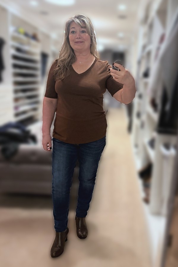 Mirror selfie of a woman wearing a brown V-neck tee, dark jeggings and brown ankle boots