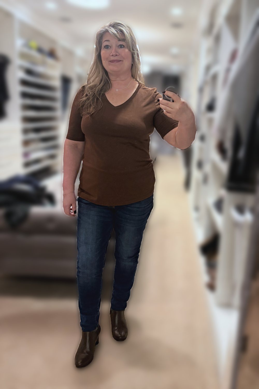 Mirror selfie of a woman wearing a brown V-neck tee, dark jeggings and brown ankle boots